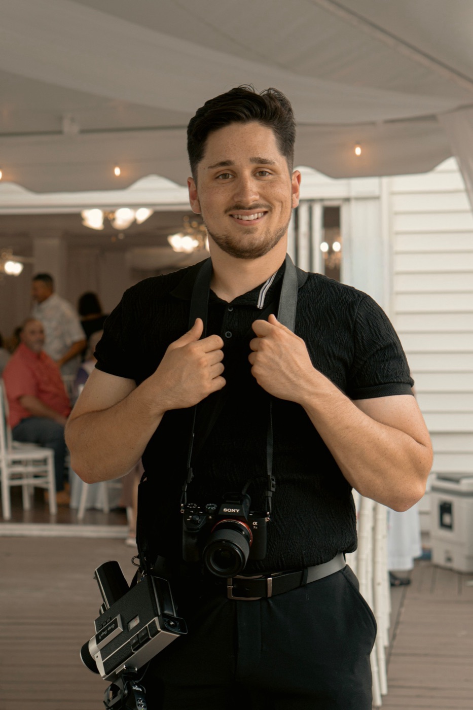 Founder of Framework Media holding a Sony camera and a vintage Super 8 camera at a wedding venue